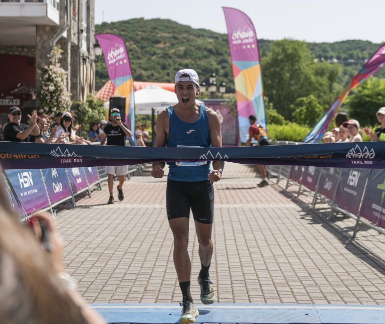Corredor de montaña cruzando la línea de meta y rompiendo la cinta de campeón en la carrera Riaño Trail Run.