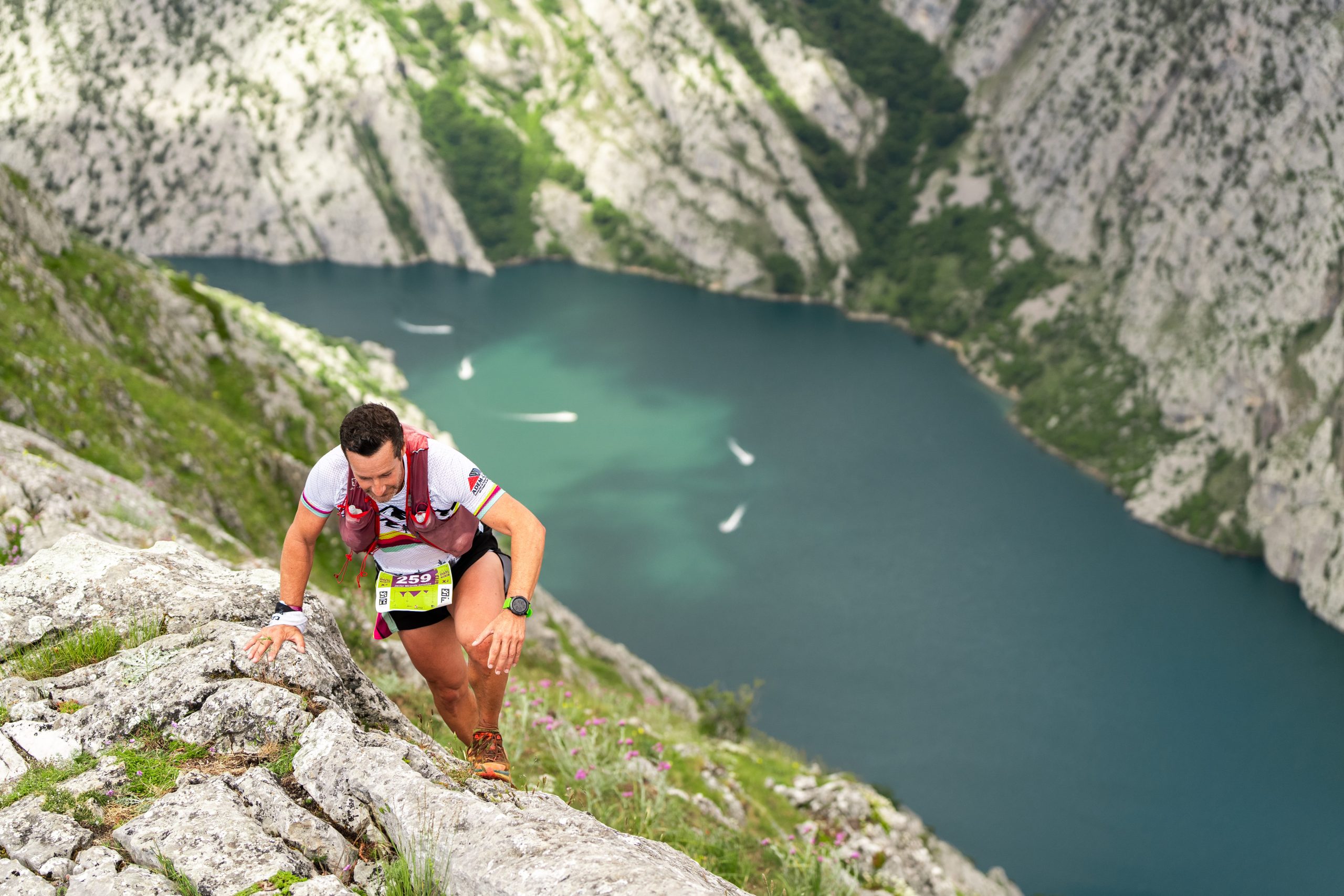 Corredor de trail running ascendiendo una cresta sobre el Embalse de Riaño durante la Riaño Trail Run en los Picos de Europa